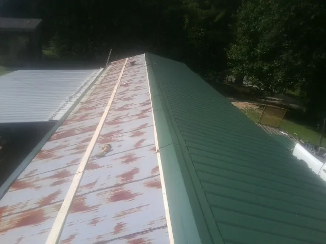 Old rusted panels beside newly installed green metal roofing — Wind Damage Roof Repair by Roofing Brothers in Whiteland
