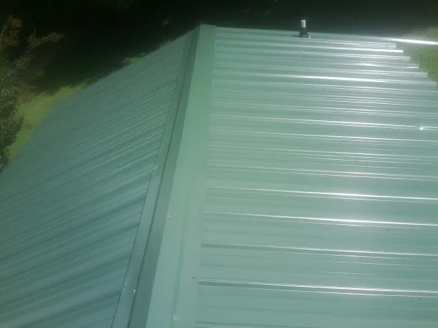 New green metal panels meeting at the ridge of a roof — Flat Roof Repair work by our crew in Whiteland