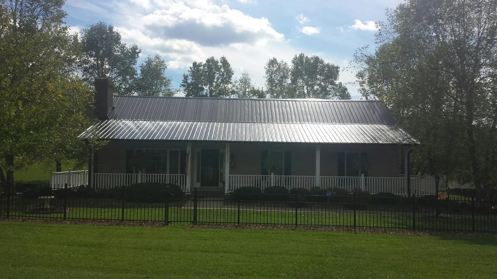 Gray metal roof on a brick ranch with a full width front porch — Gutter Guard Installation work by our crew in Whiteland