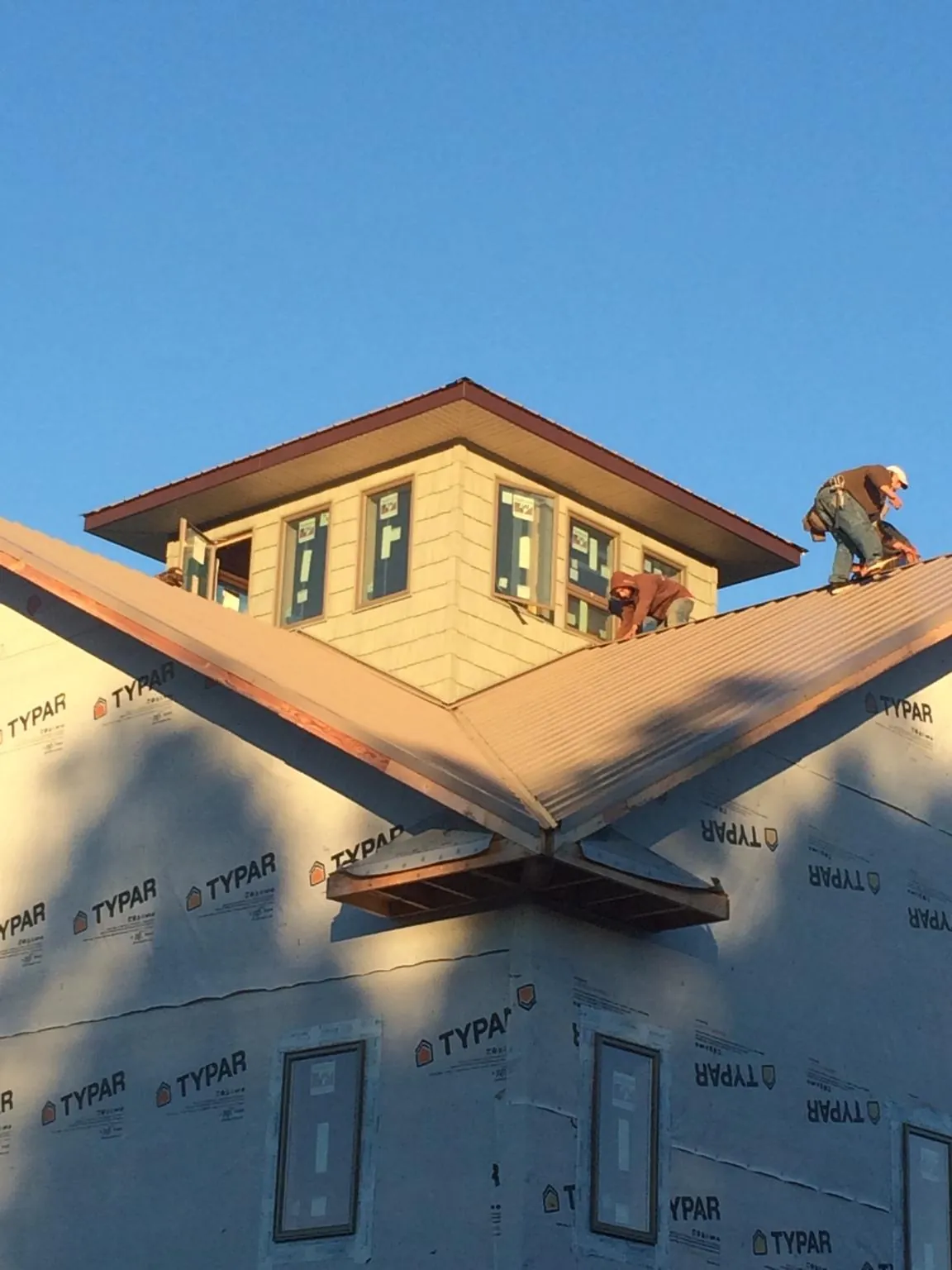 Roofers working around a rooftop cupola on a new metal roof at sunset — Roof Waterproofing in Whiteland by Roofing Brothers